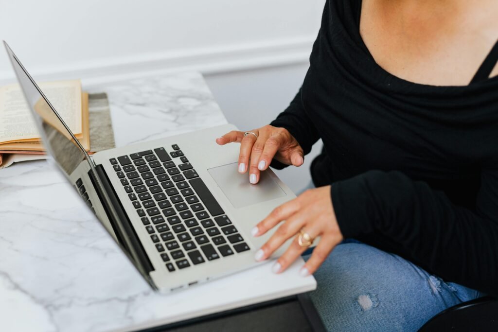 A person using a laptop on a marble desk, typing and focusing on work indoors.